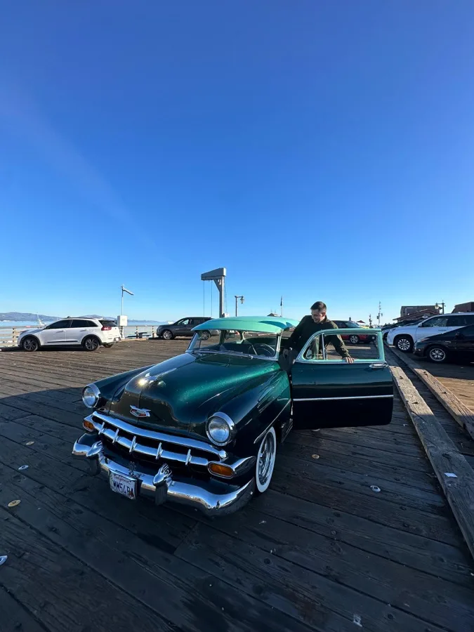 Felipe beside a classic car on a pier